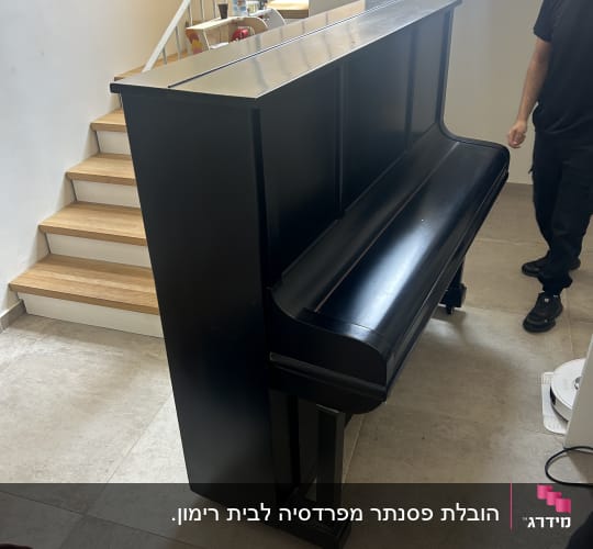 פסנתר שחור ליד גרם מדרגות עם אדם לידו